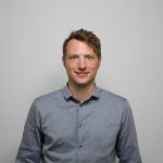 A chest-up portrait of Philipp Reiter against a grey background